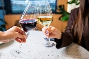 Two,Elegant,Wine,Glasses,Clink,Together,In,Celebration,,One,Filled